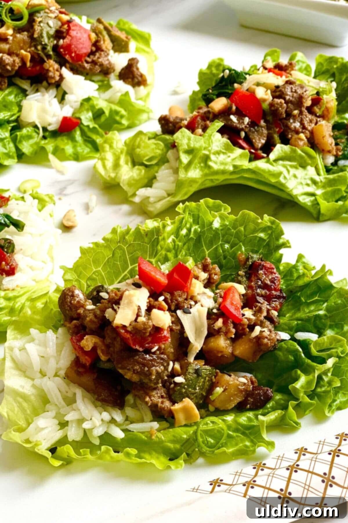 Savory Beef Lettuce Cups 2 Crisp lettuce cup filled with savory Korean beef and fluffy white rice, garnished with green onions and sesame seeds.