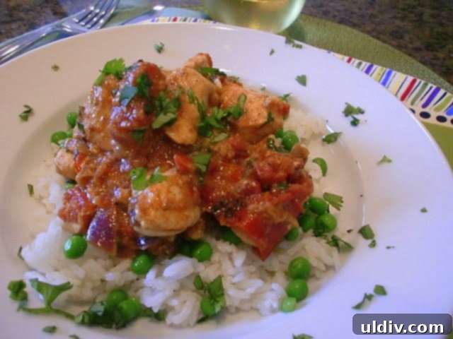 Creamy Chicken Tikka Masala served alongside fluffy basmati rice and bright green peas, ready to be enjoyed.