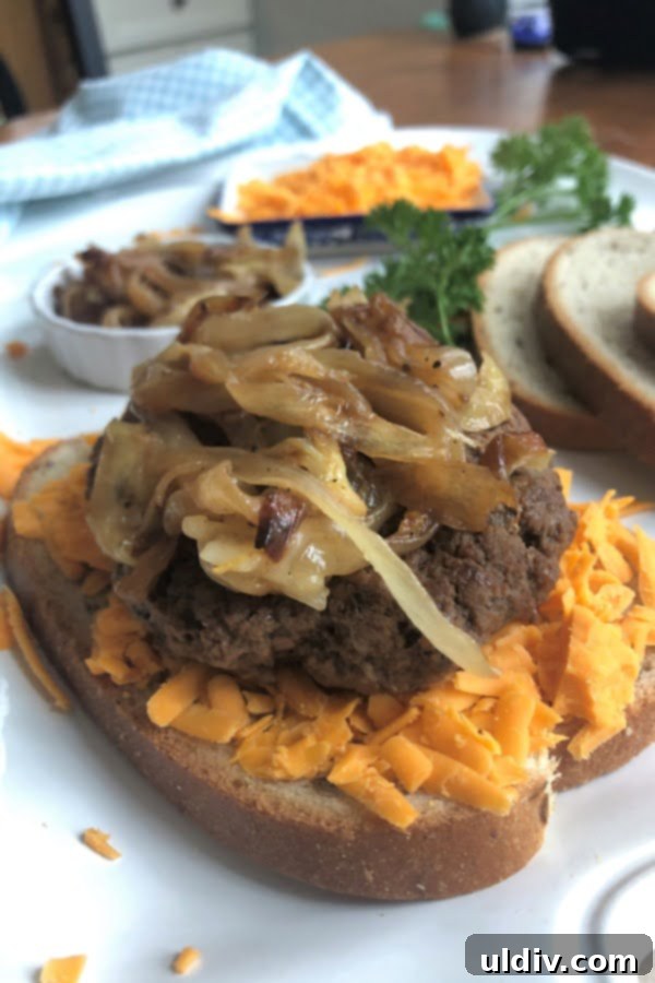 Decadent Caramelized Onion Patty Melt 4 Close up of sandwich with caramelized onions, cheddar cheese, and rye bread in background