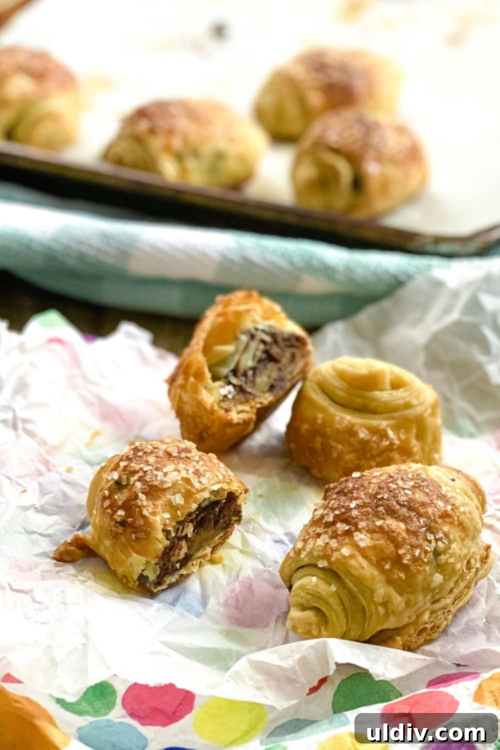Flaky Chocolate Puff Bites 6 a baking sheet filled with freshly baked chocolate puff pastry rolls alongside a small serving plate