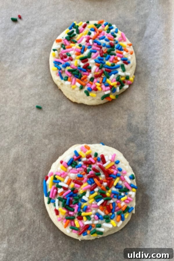 Drop-and-Done Sugar Cookies: Pure Perfection, Zero Fuss 5 Two freshly baked sugar cookies, generously covered with rainbow sprinkles, cooling on parchment paper.