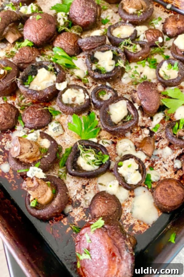 Tangy Blue Cheese Garlic Butter Mushrooms 4 baked mushrooms with herbs on a baking sheet