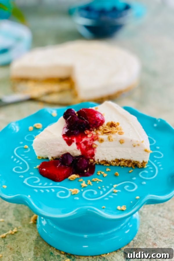 Dreamy No-Bake Strawberry Cheesecake with Berry Coulis 2 A perfectly sliced no bake strawberry cheesecake with a generous topping of fresh berry sauce, highlighting its creamy texture and crunchy granola crust.