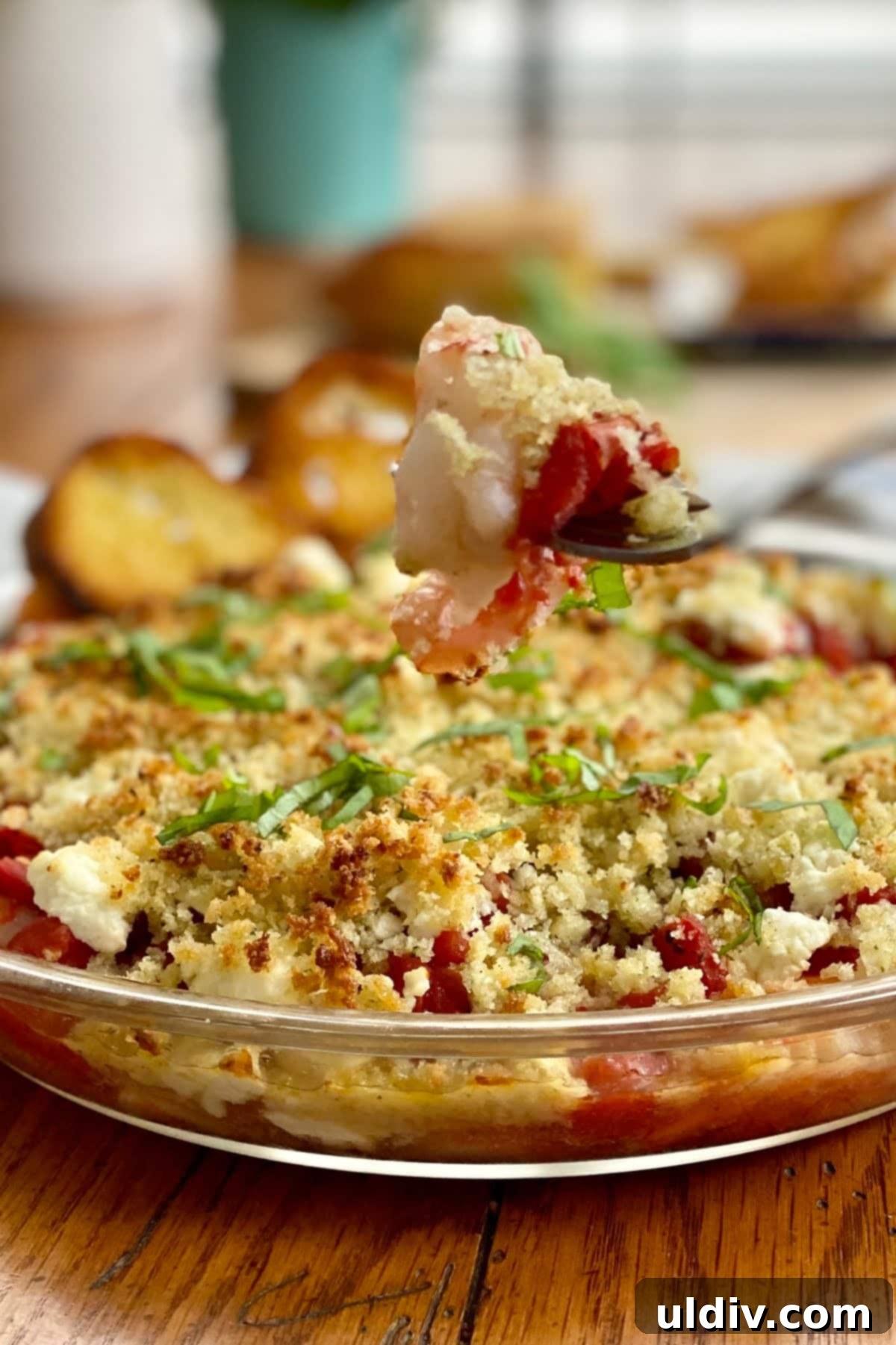 Mediterranean Feta Shrimp Bake 7 A single baked shrimp with feta and tomatoes on a fork, showcasing the tender shrimp, melted feta, and bits of tomato.