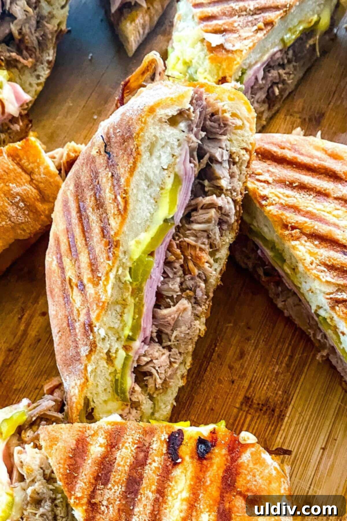 Instant Pot Cuban Pork Sandwiches 2 A freshly pressed Cuban pork sandwich, perfectly cut in half to reveal its mouth-watering layers of shredded pork, ham, Swiss cheese, and pickles.