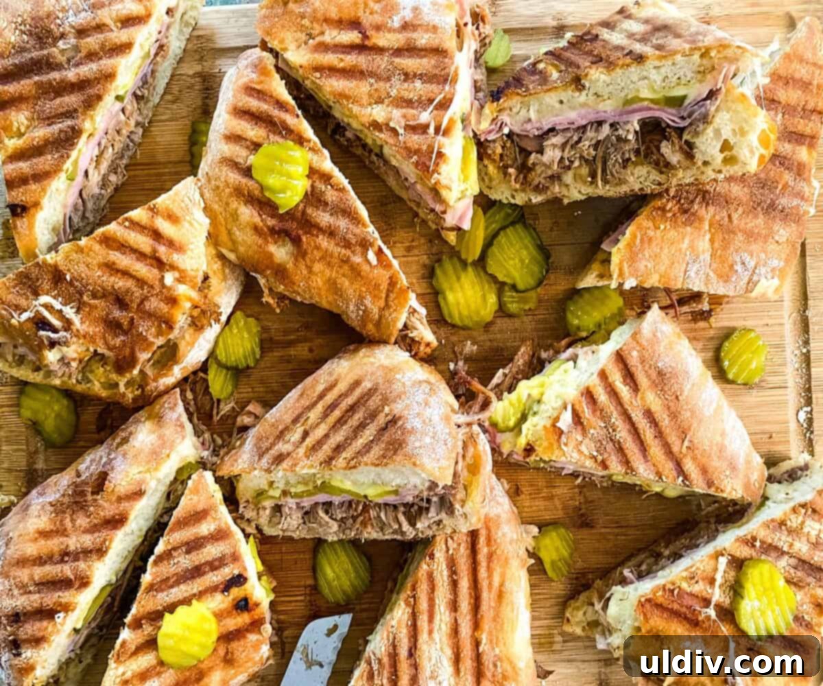 Instant Pot Cuban Pork Sandwiches 4 A cutting board laden with several freshly pressed Cuban pulled pork sandwiches, showcasing their crispy bread and savory fillings.