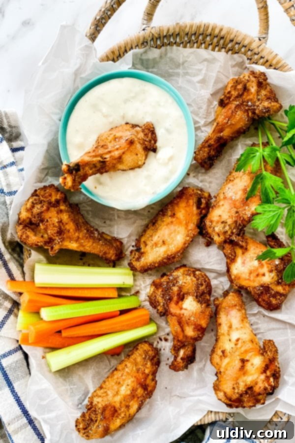 Ultimate Oven-Baked Wings 2 baked chicken wings with a side of blue cheese dip, garnished with fresh herbs, showcasing their golden and crispy texture