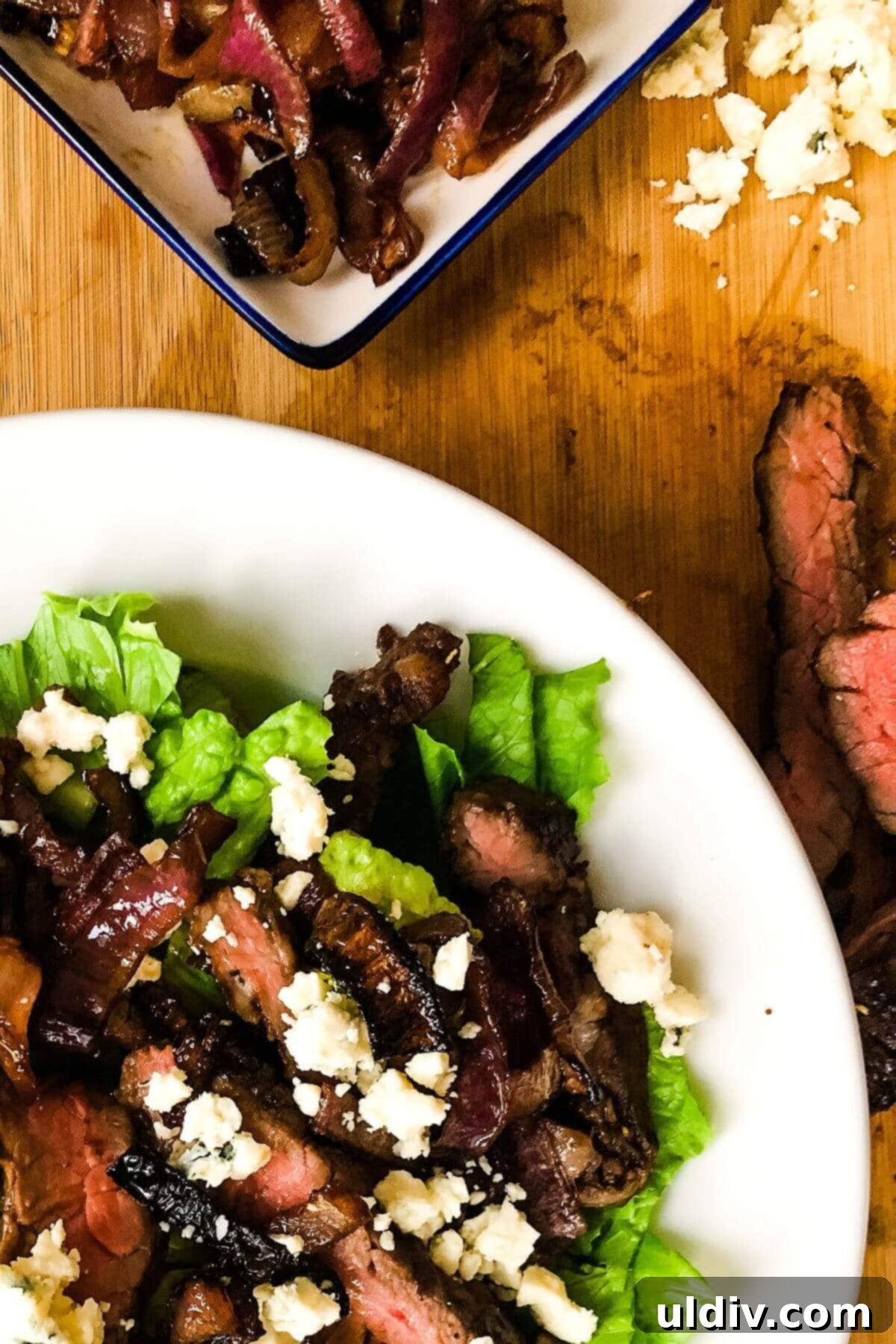 Balsamic Herb Grilled Steak Salad with Crumbled Blue Cheese 13 A beautiful close-up of a grilled steak salad, highlighting the distinct components: tender steak, roasted onions, blue cheese, and crisp lettuce.