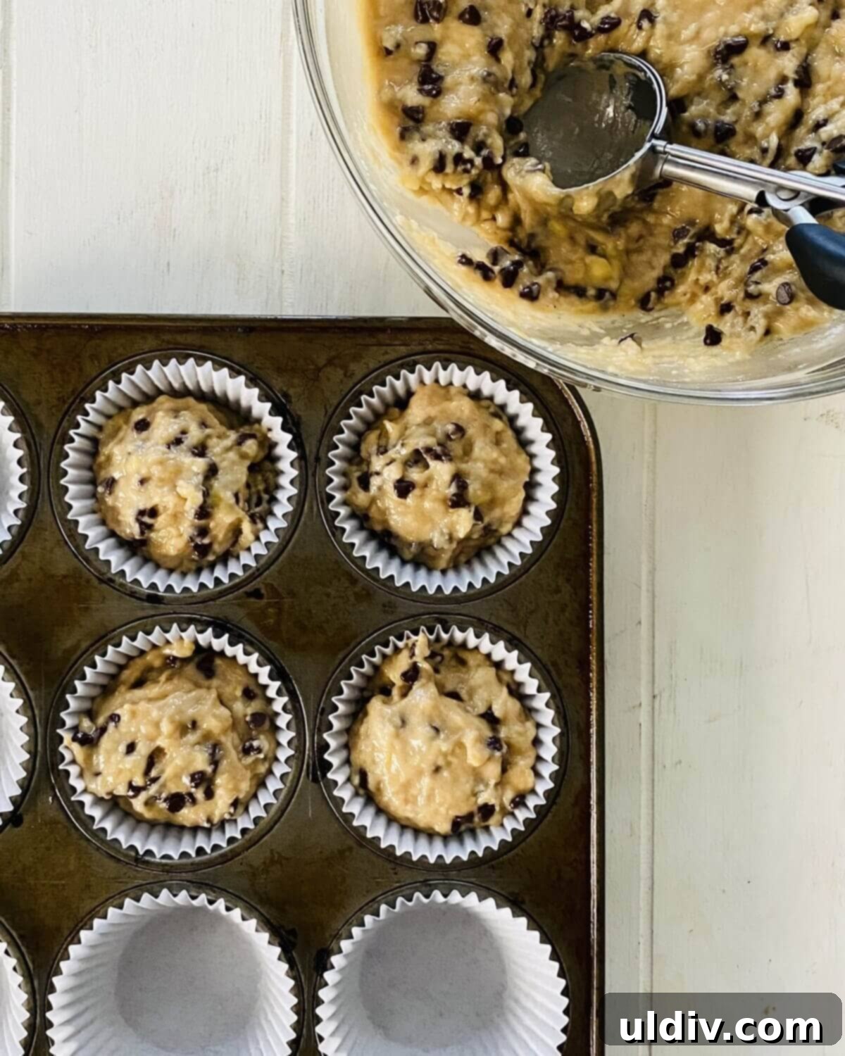 Irresistible Vegan Banana Muffins 10 Scooping dairy-free banana muffin batter into a muffin pan lined with paper cups.