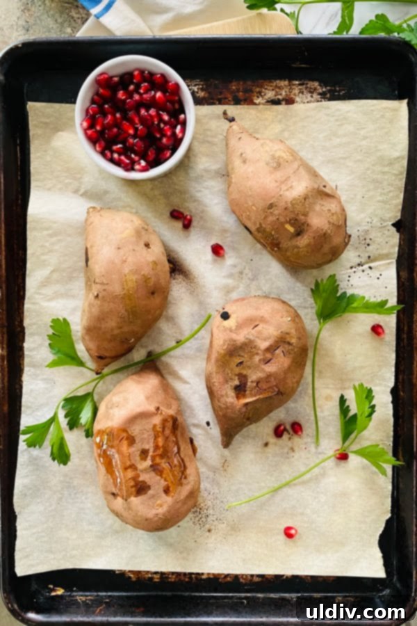 Loaded Sweet Potatoes: Apple, Bacon & Pomegranate 4 Perfectly baked sweet potatoes resting on a parchment-lined baking sheet, ready for scooping and stuffing.