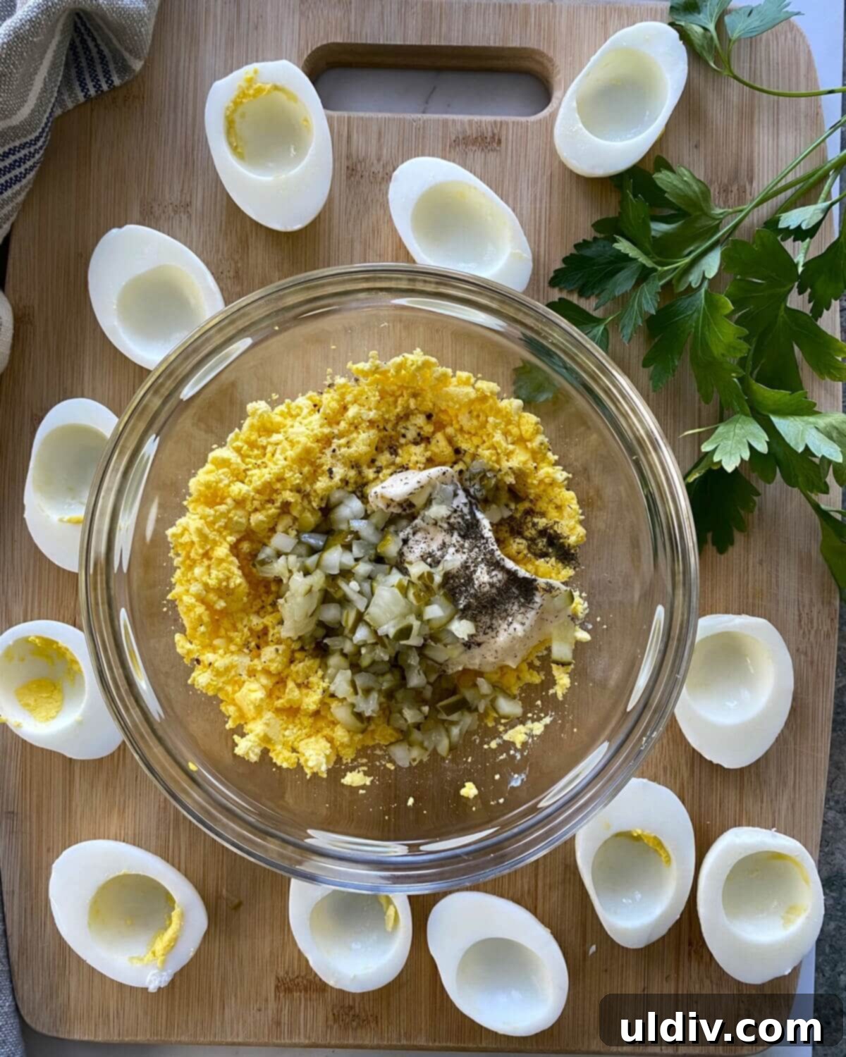 Zingy Dill Pickle Deviled Eggs 9 Ingredients for deviled eggs in a glass bowl.