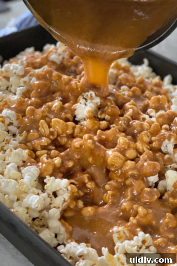 Irresistible Homemade Salted Caramel Popcorn 4 Hot, golden, and glossy homemade caramel sauce being carefully poured over a mountain of freshly popped popcorn in a large metal mixing bowl, ensuring even coating.