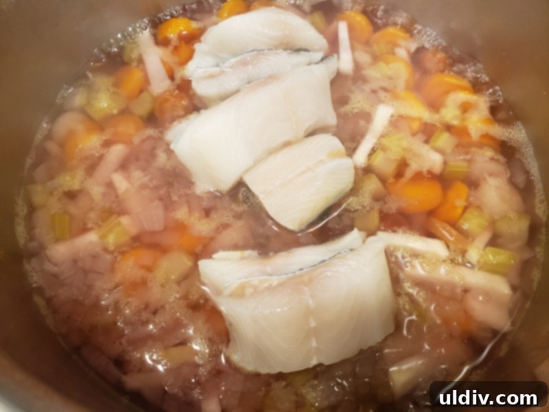 Autumn's Health Elixir: Dive Into Delicious Fish Soup 8 Fish pieces being added to a simmering pot of vegetable broth.