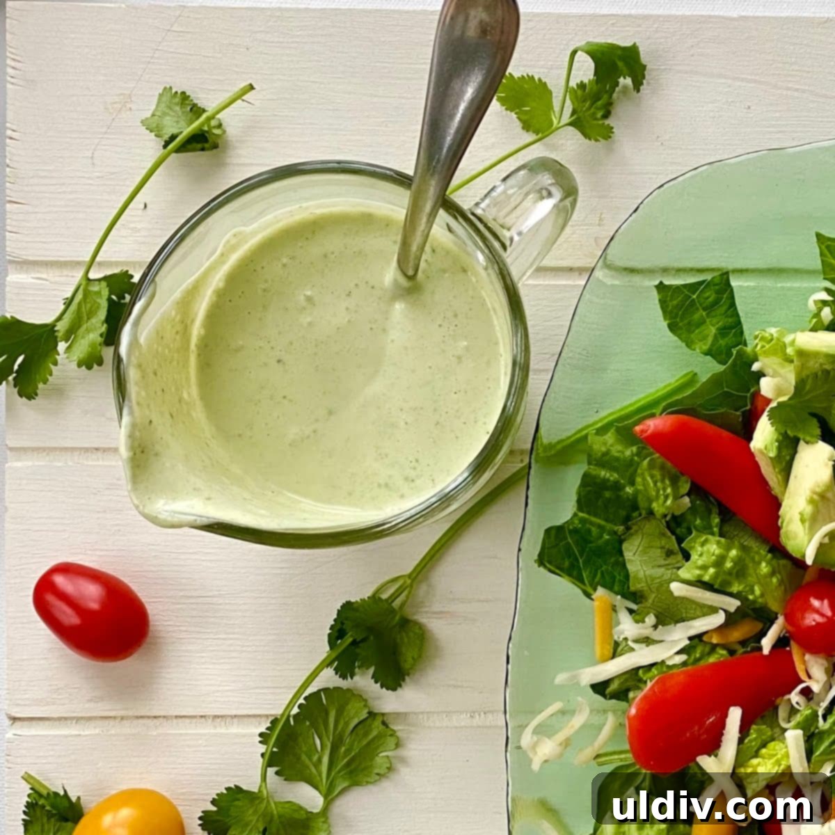 A pitcher of creamy cilantro lime dressing, garnished with lime slices and cilantro.