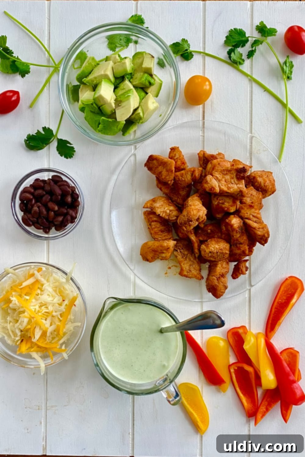 Close-up of a Southwest Chicken Salad featuring chipotle seasoned chicken, colorful bell peppers, creamy avocado, shredded pepper jack cheese, black beans, and a generous drizzle of cilantro lime dressing.