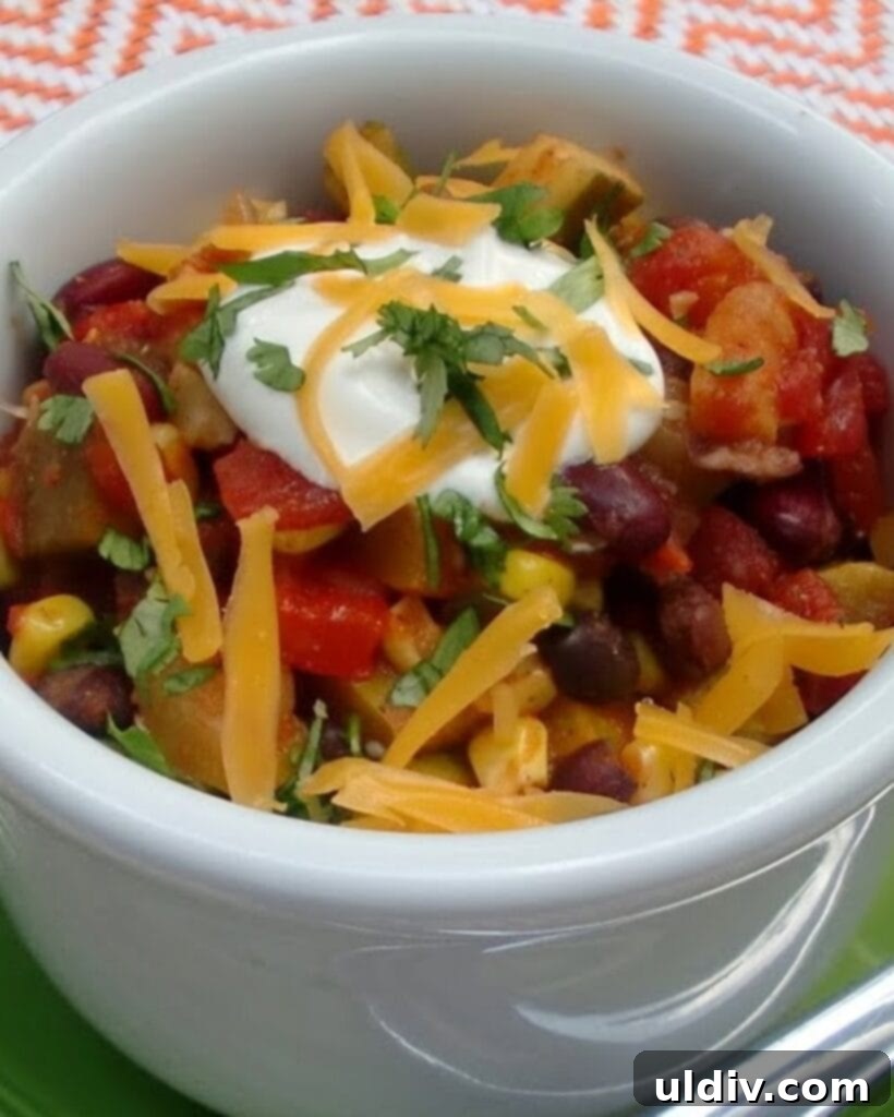 A bowl of vegetable chili topped with melted cheddar cheese.