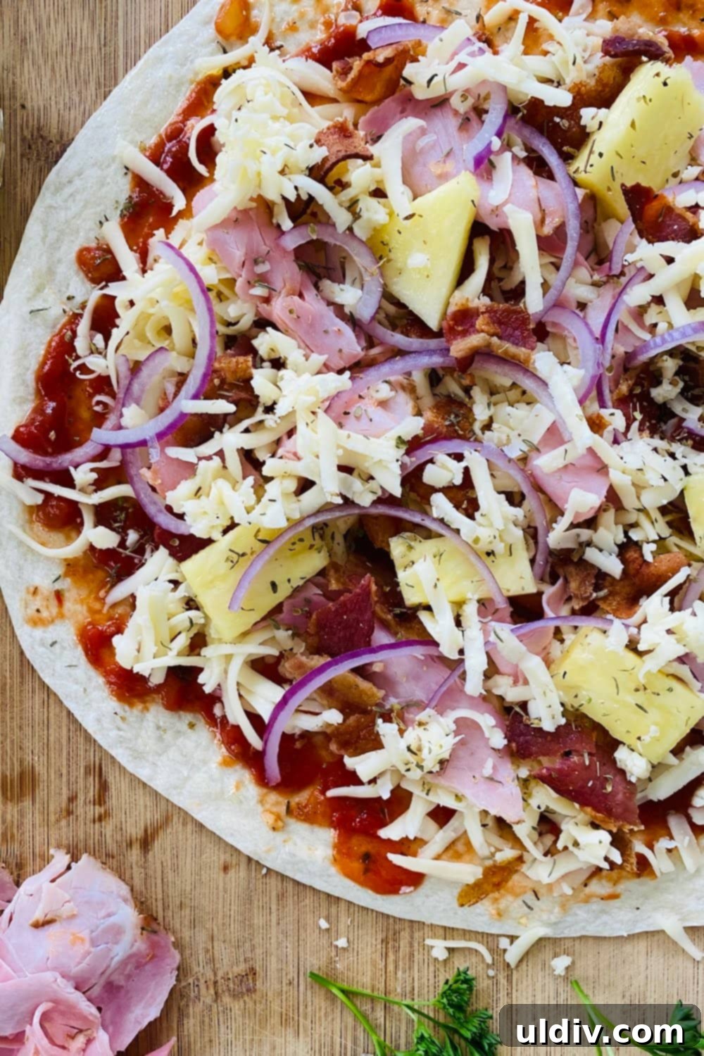 Hawaiian Pizza Tortillas 3 A Hawaiian Tortilla Pizza, unbaked and ready for the oven, topped with ham, bacon, pineapple, and cheese.