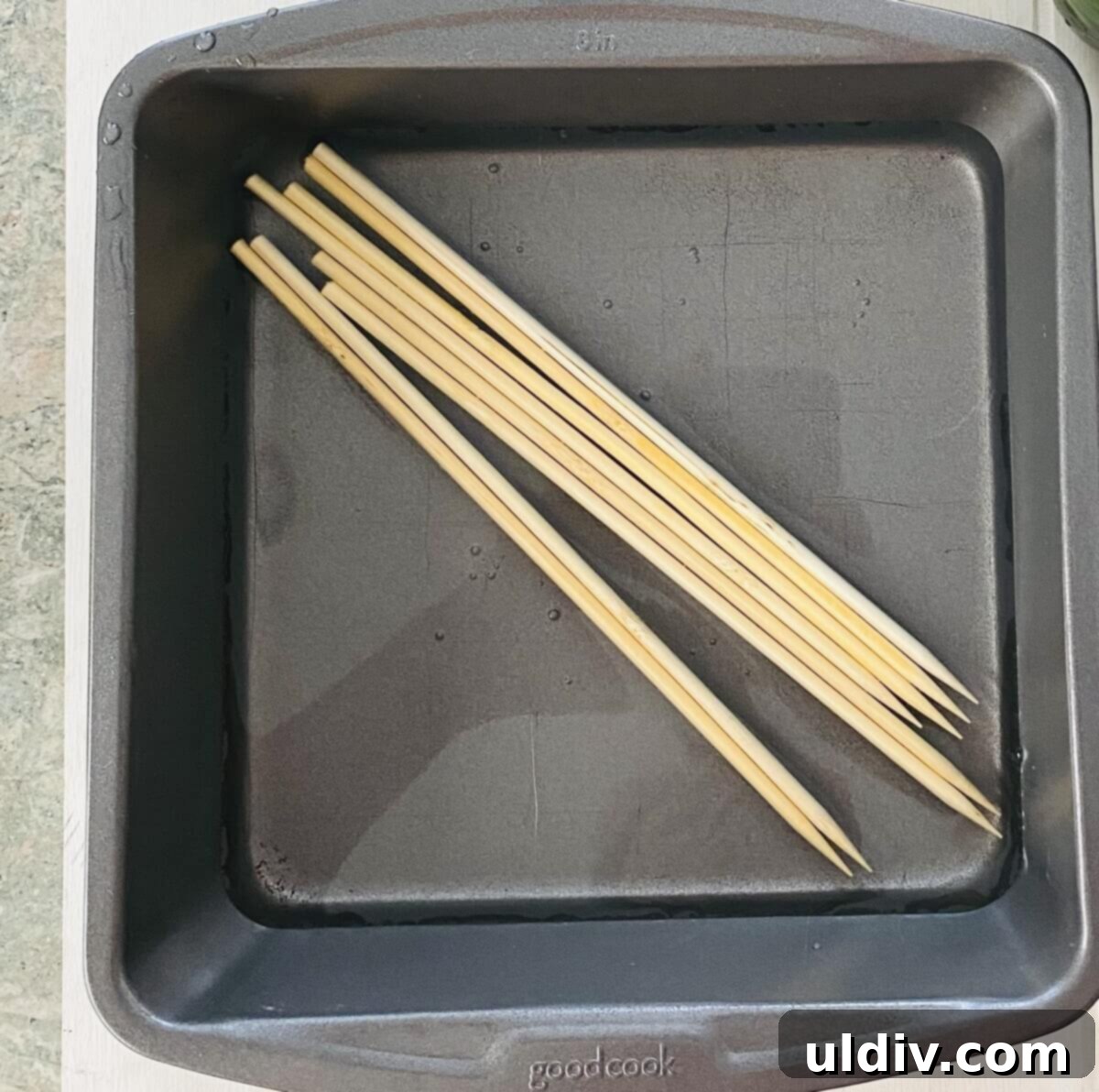Tangy Glazed Shrimp Skewers 4 Wooden skewers soaking in a bowl of cold water to prevent burning on the grill.