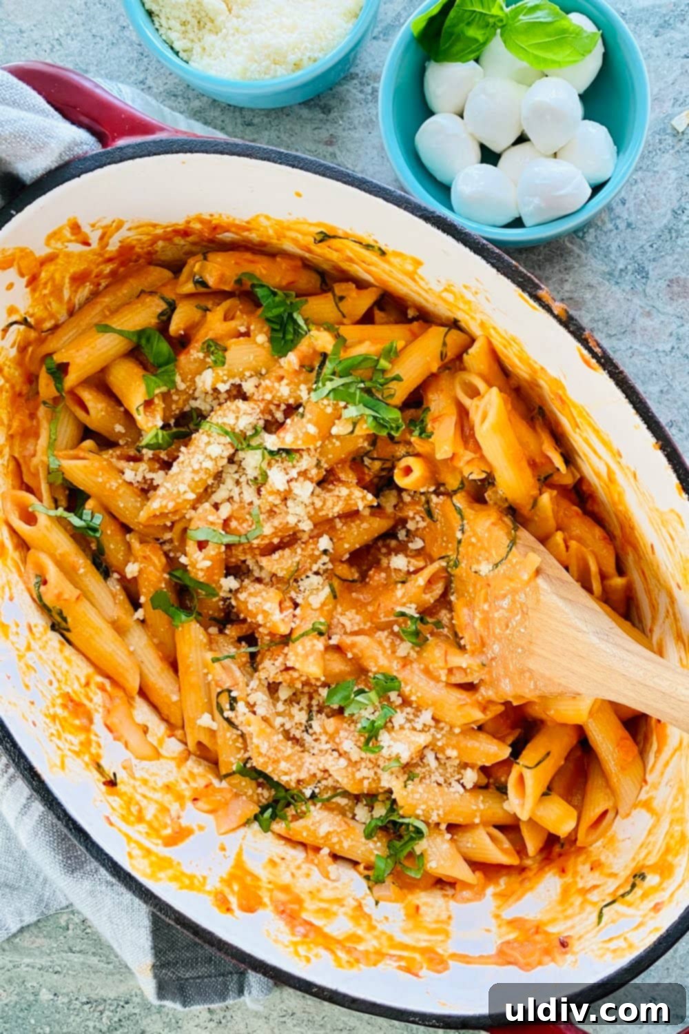 Velvety Tomato Pasta 5 A large pot filled with creamy tomato pasta, garnished with fresh basil leaves and grated Parmesan cheese, ready to be served.