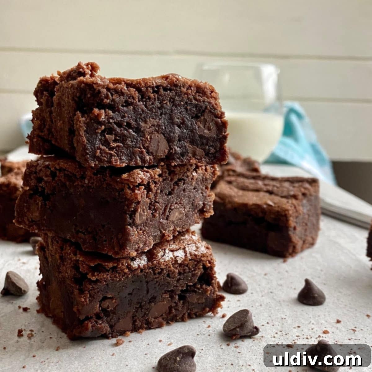 3 brownies stacked on top of each other with a glass of milk, invitingly presented.