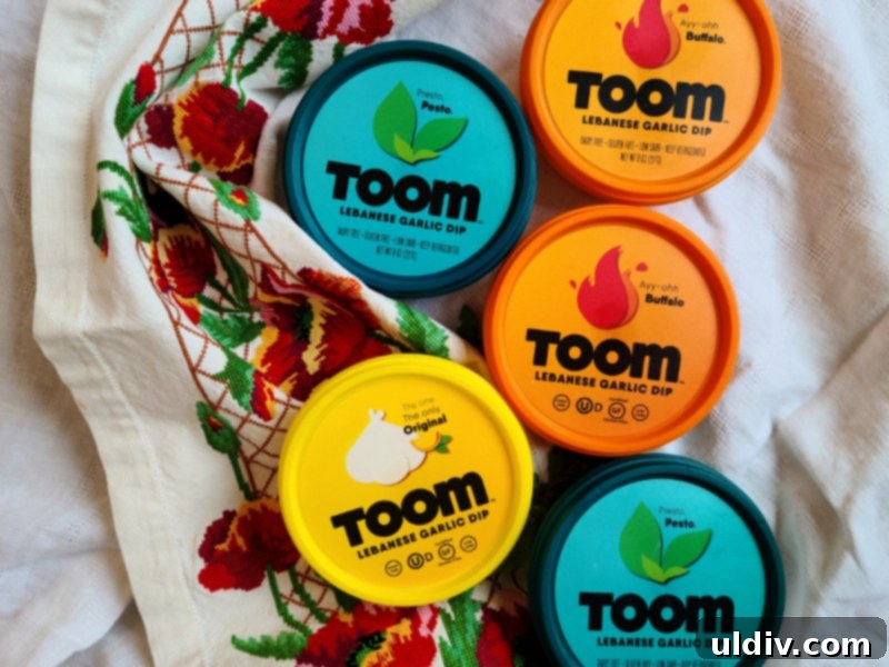 Three tubs of Toom garlic dip: Original, Pesto, and Buffalo flavors displayed together.