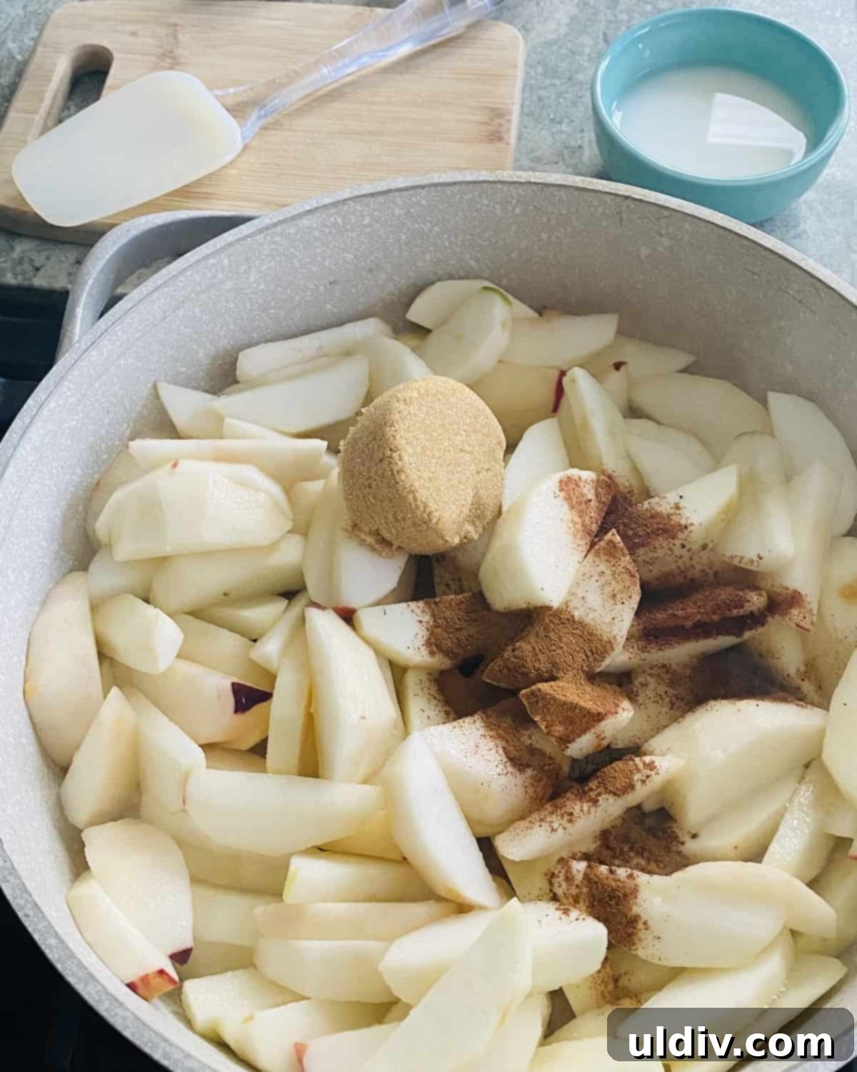 Uncooked peeled apple slices, cinnamon and brown sugar in a sauté pan.