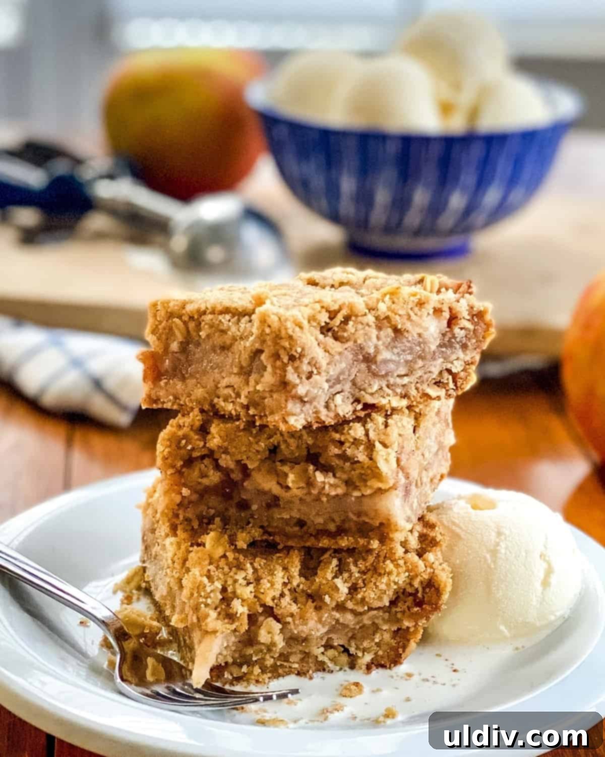 Spiced Apple Crumb Bars 9 3 apple bars stack on top of each other with vanilla ice cream in the distance