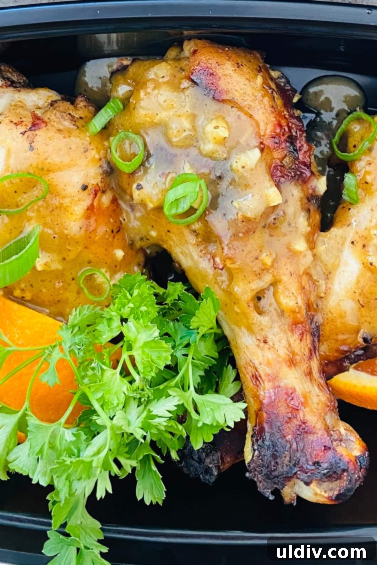 Crispy oven roasted chicken leg with a vibrant orange, mustard, and honey marinade, garnished with fresh parsley and orange wedges.