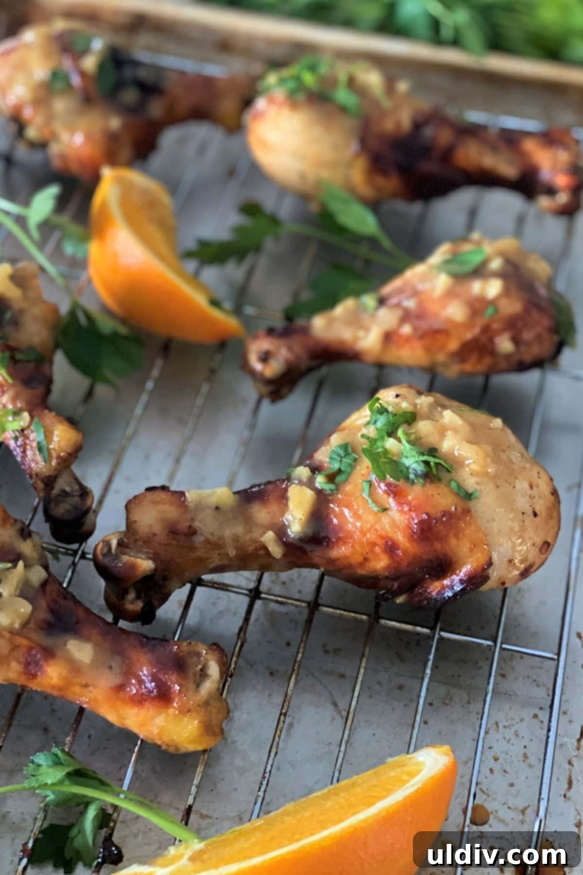Close-up of raw chicken drumsticks coated in a rich orange, Dijon mustard, and honey marinade, ready for roasting.