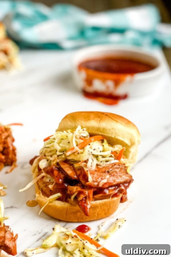 Smoky BBQ Pork Sliders with Zesty Slaw 4 A mini bbq pork tenderloin slider with cole slaw and bbq sauce, showcasing a perfect single serving.