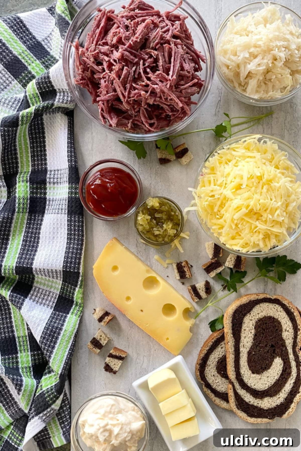 Irresistible Reuben Casserole 4 A selection of fresh ingredients laid out on a counter, including corned beef, Swiss cheese, sauerkraut, slices of rye bread, ketchup, mayonnaise, and sweet pickle relish, ready for the Reuben casserole.