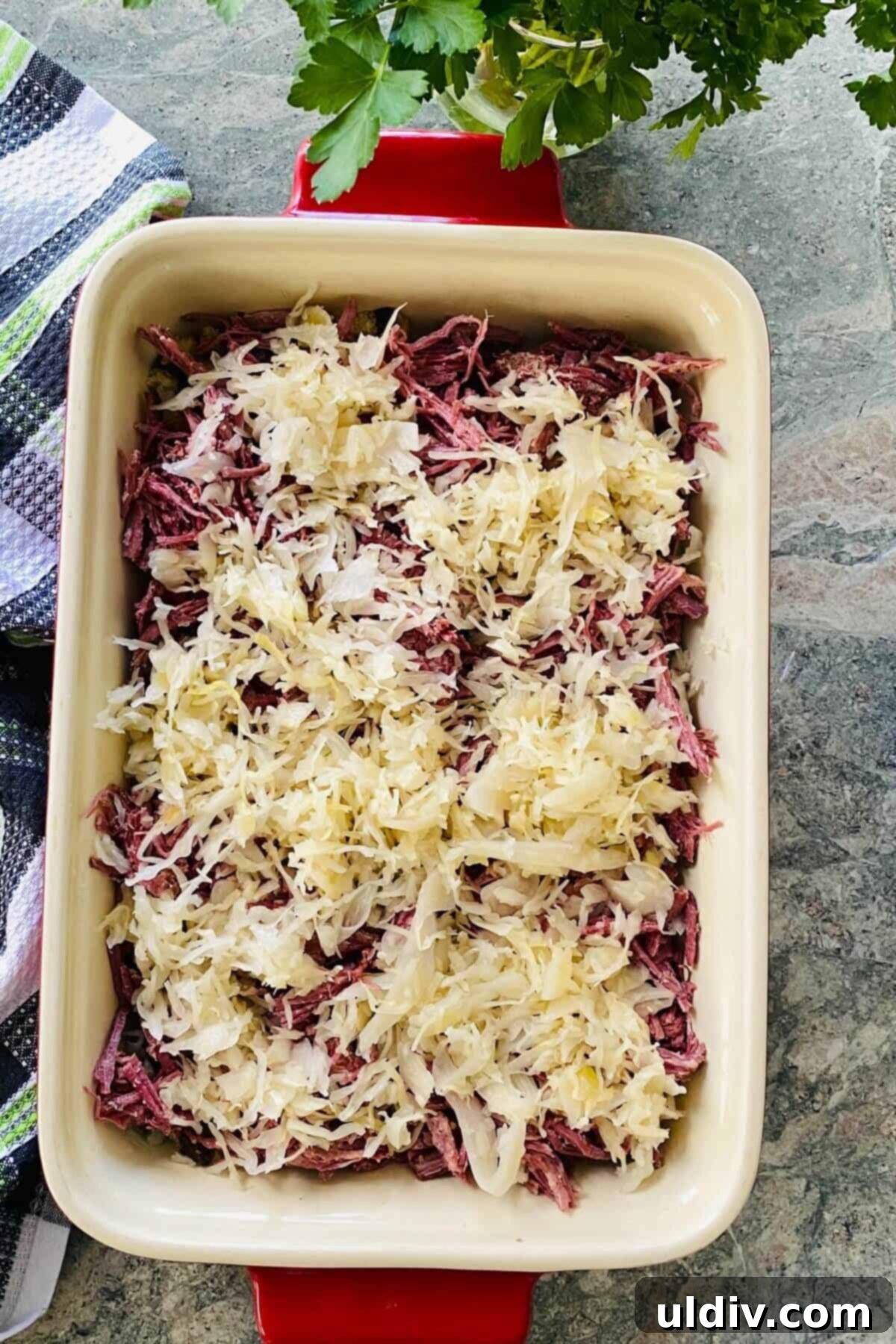 Irresistible Reuben Casserole 6 A layer of tangy sauerkraut evenly distributed over the corned beef in the Reuben casserole, preparing for the next layer of dressing.