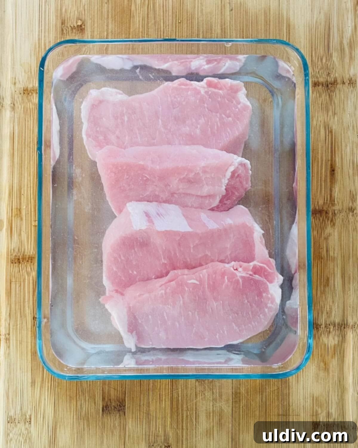 Pork chops soaking in a brining solution within a large bowl, indicating the initial preparation step for enhanced tenderness.