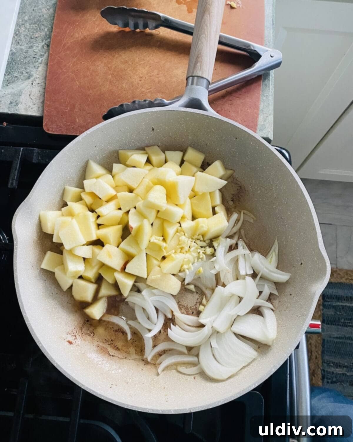 Sliced apples, onions, and minced garlic sautéing in the same pan, forming the aromatic base for the sauce.