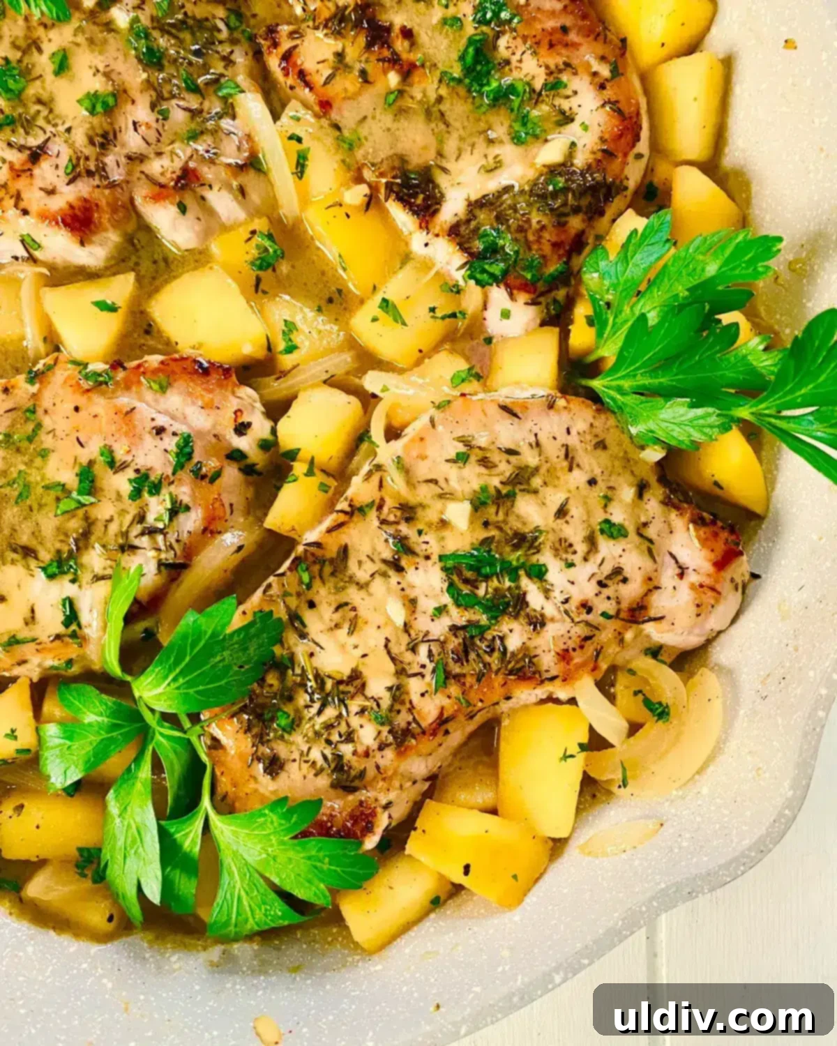 A sauté pan displaying cooked pork chops with the savory apple and onion sauce, ready to be served.