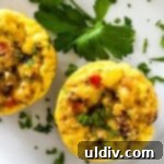 Two muffin tin eggs on a plate, garnished and ready to eat.
