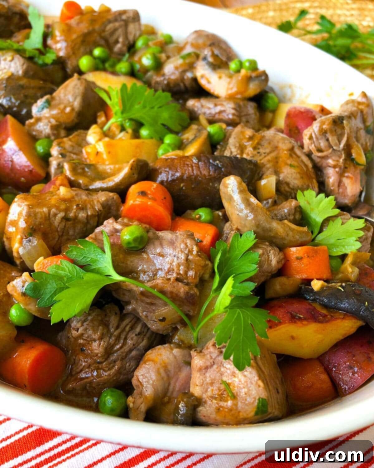 Beef Tenderloin, Mushroom & Potato Stew 2 A beautifully plated dish of beef tenderloin stew, showcasing tender beef, new potatoes, and mushrooms, garnished with fresh herbs.