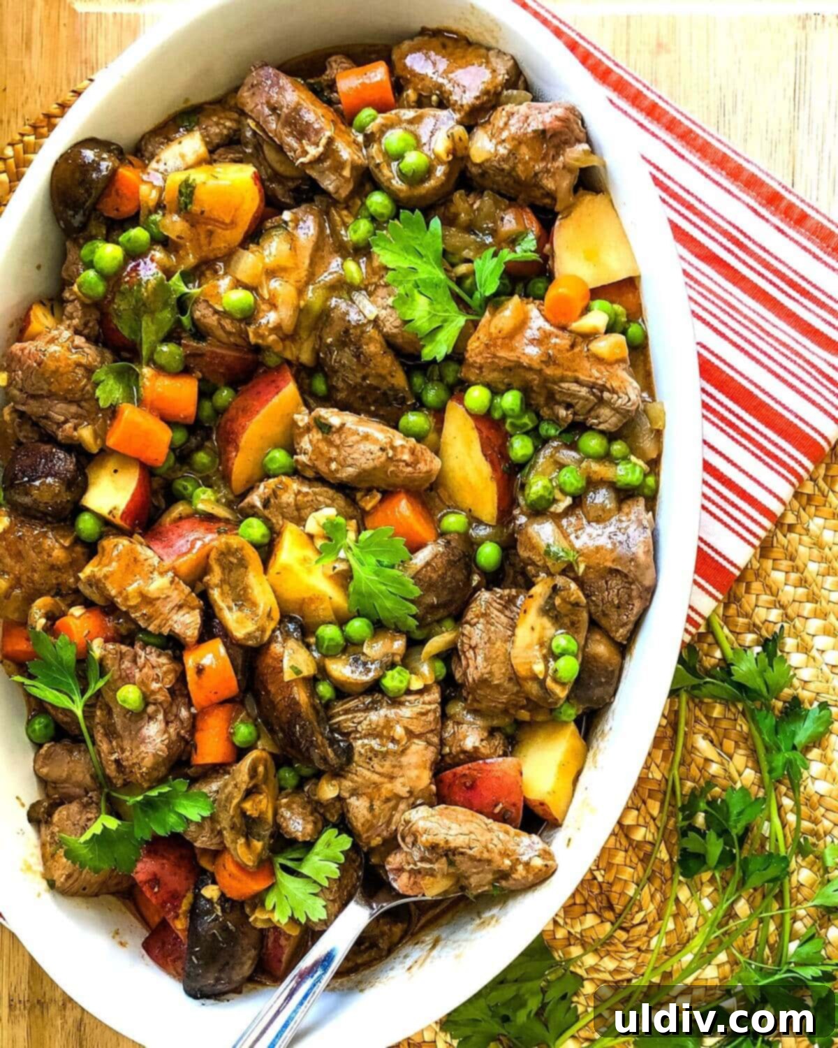 Beef Tenderloin, Mushroom & Potato Stew 3 A serving dish filled with rich beef tenderloin stew, featuring chunks of beef, new potatoes, carrots, and mushrooms, garnished with fresh parsley.
