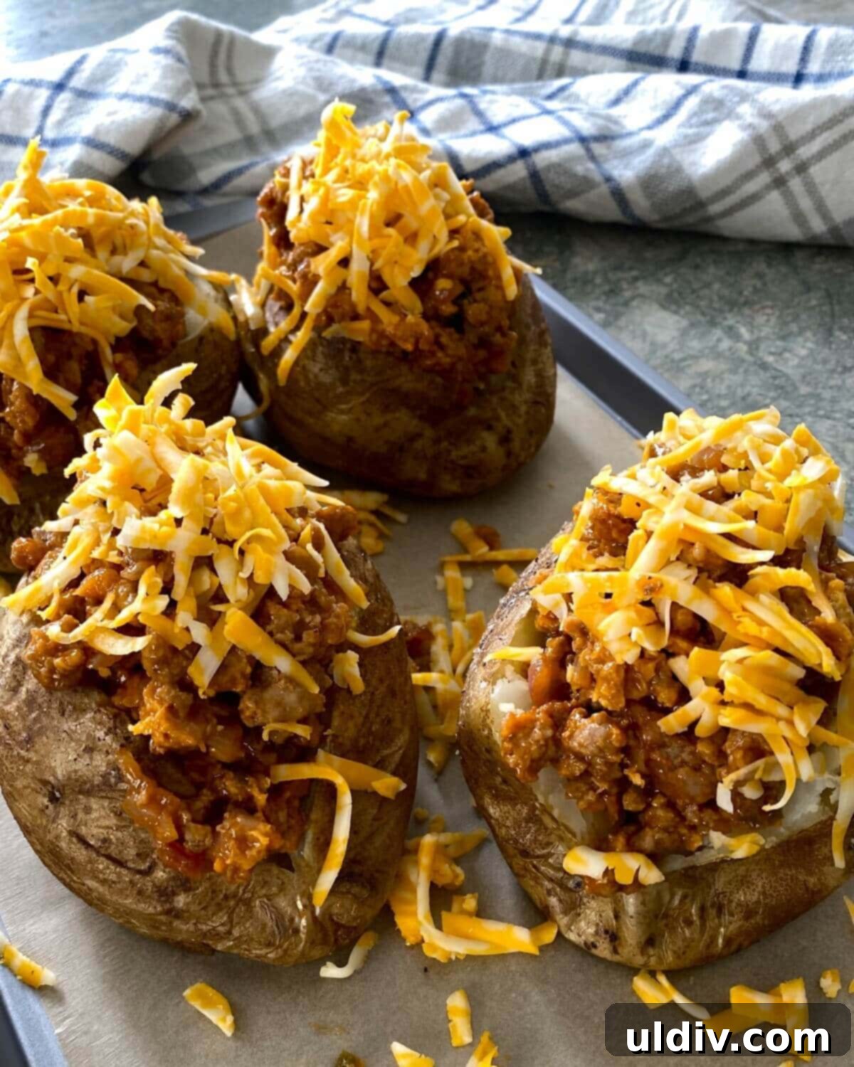 Turkey Sloppy Joe Potato Bake 7 Stuffed sloppy joe potatoes topped with a generous layer of shredded sharp cheddar cheese, awaiting their final bake in the oven.