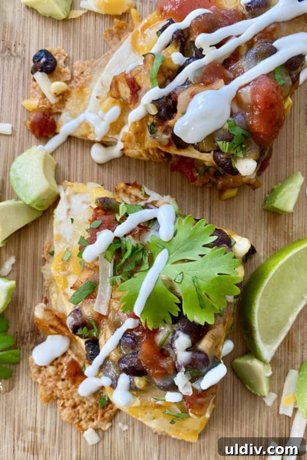 Tex-Mex Layered Fiesta with Cheesy Chicken, Sweet Corn and Black Beans 2 A perfectly baked wedge of a Tex-Mex cheesy chicken, corn, and black bean tortilla stack, garnished with fresh cilantro and a dollop of sour cream, ready to be served as a festive and flavorful meal.