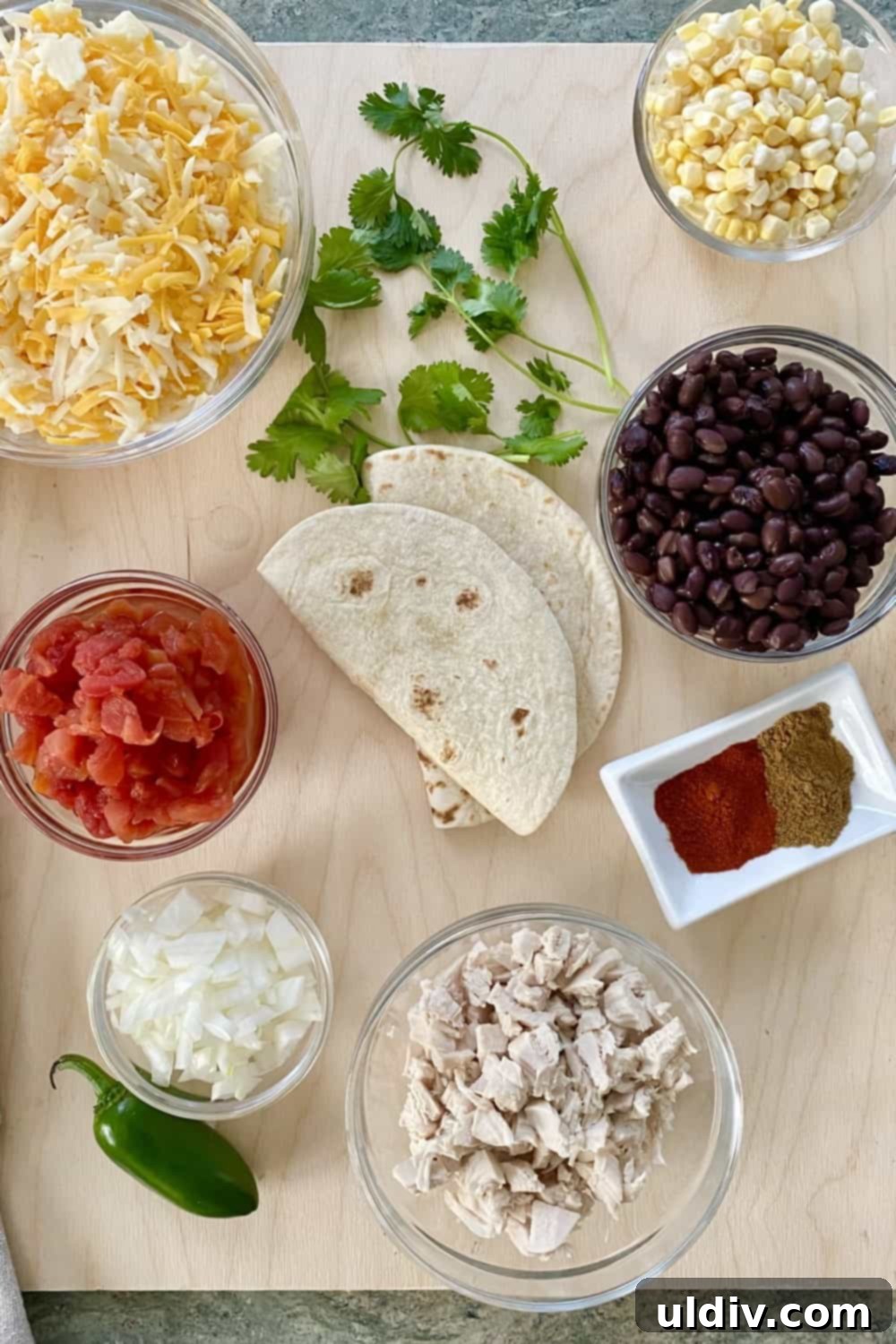 Tex-Mex Layered Fiesta with Cheesy Chicken, Sweet Corn and Black Beans 4 All the fresh ingredients laid out before preparation for Tex-Mex chicken, corn, and black bean tortilla stacks, including tortillas, cooked chicken, black beans, cheese, tomatoes, onions, and corn.
