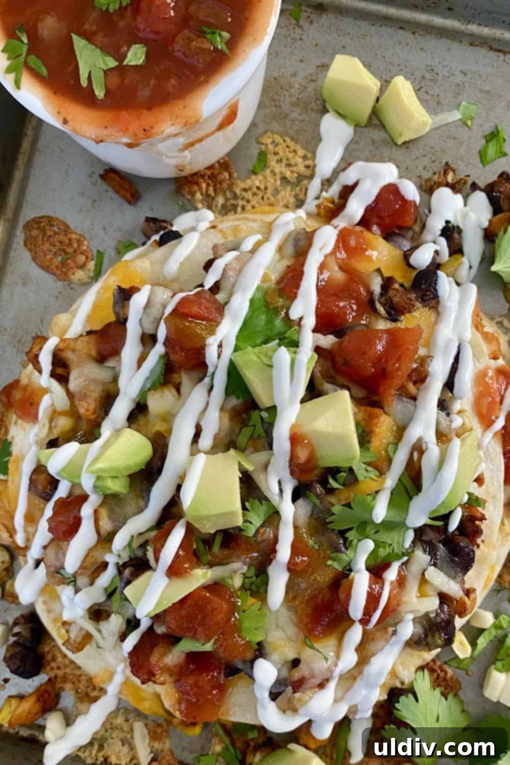 A perfectly baked tortilla stack wedge, topped with a dollop of sour cream and fresh cilantro, ready to be enjoyed.
