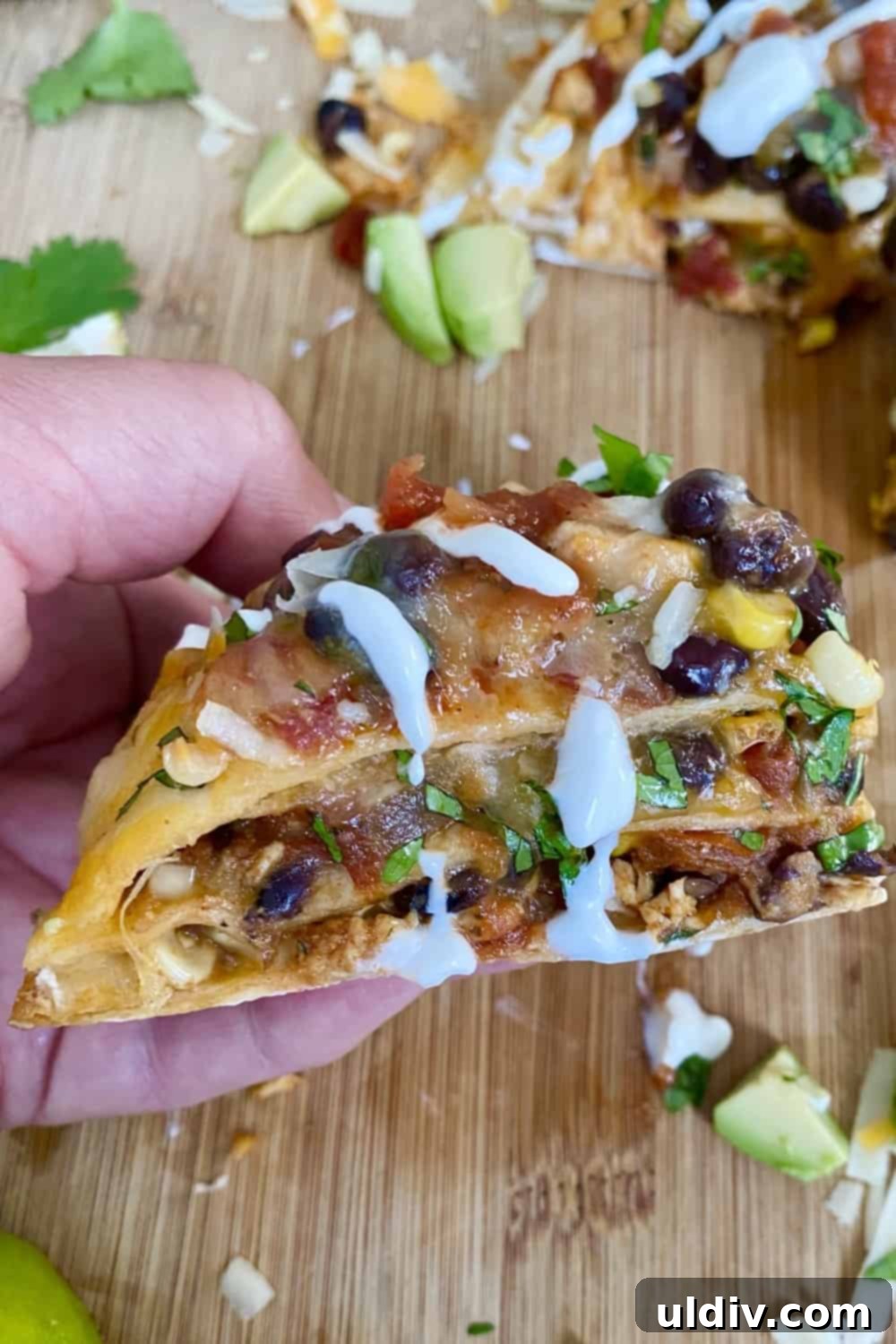 A close-up view of a baked tortilla stack wedge, showcasing the golden-brown tortilla and the rich, cheesy filling.
