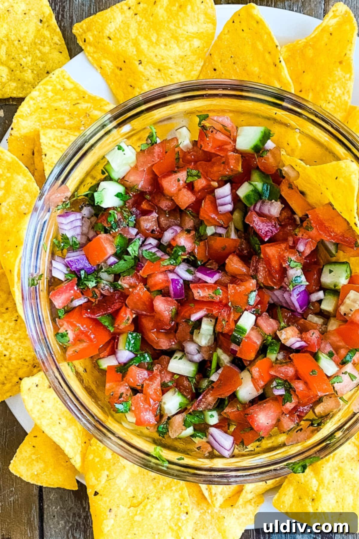 Bright & Zesty Pico 8 A generous bowl of easy homemade Pico de Gallo without jalapenos, featuring perfectly chopped tomatoes, cucumbers, red onions, and cilantro, served with crispy tortilla chips.