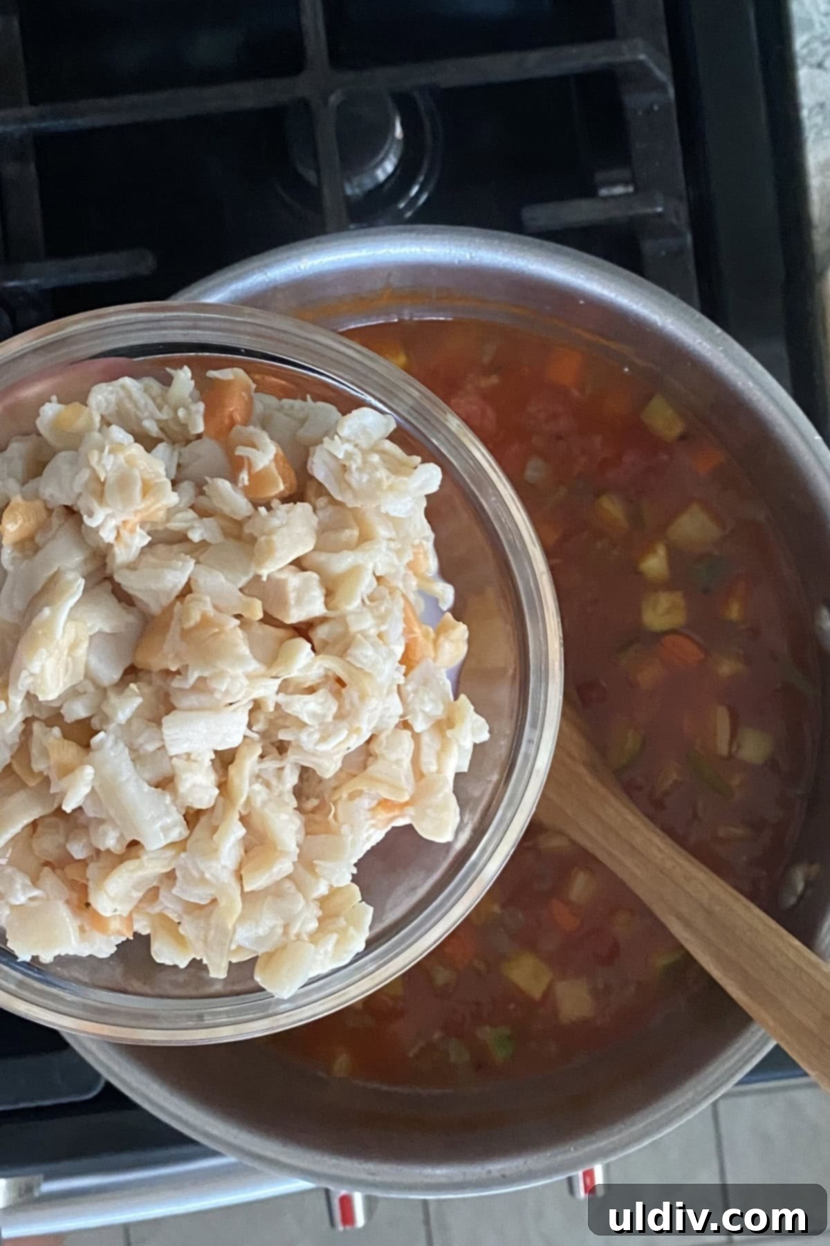 Grandma's Classic Manhattan Clam Chowder Recipe 6 Crushed tomatoes and clam juice added to the sautéed vegetables, beginning to form the rich, red broth of the Manhattan clam chowder, simmering gently.