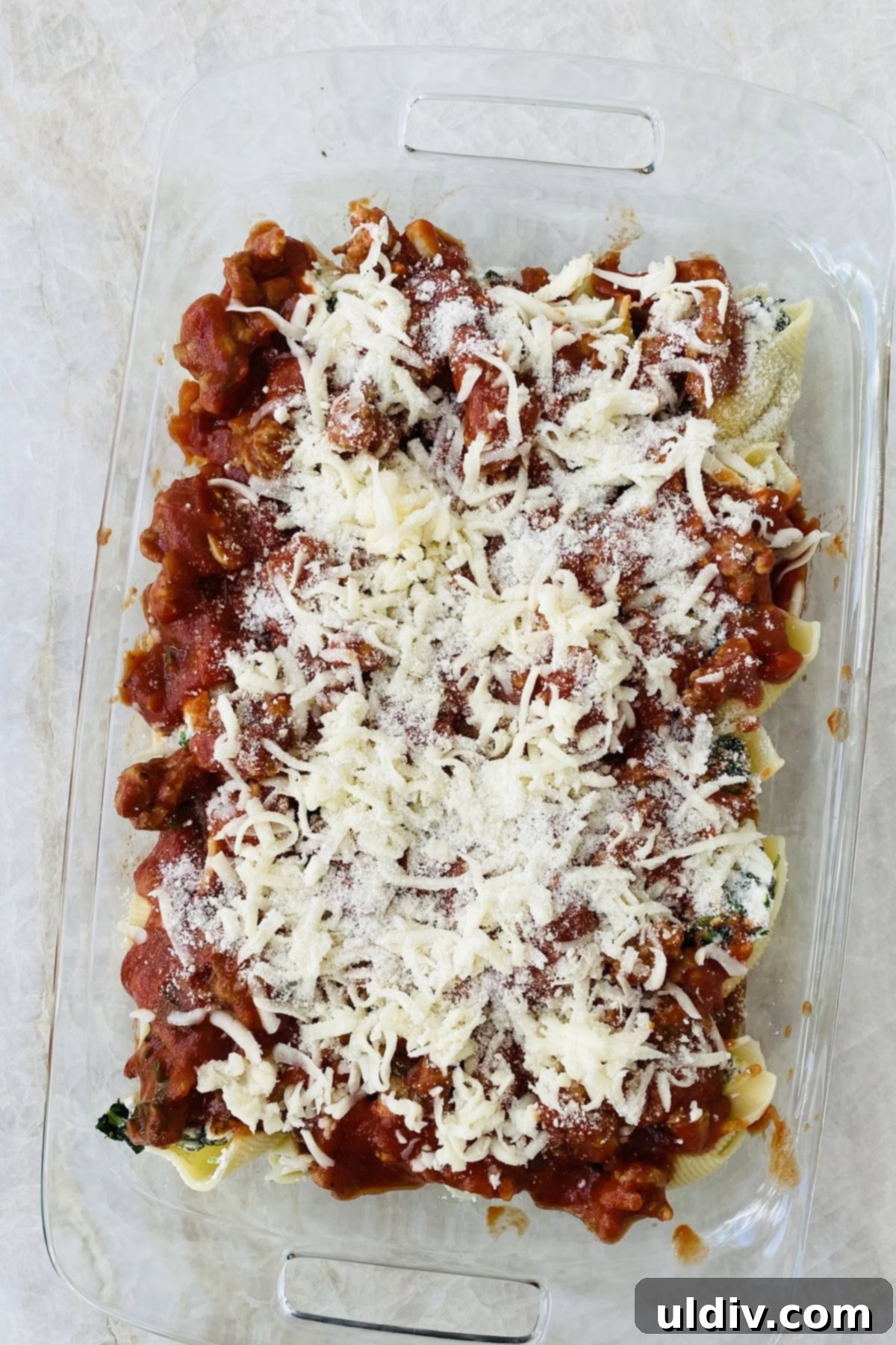 Italian Sausage Stuffed Shells 5 An unbaked pan of beautifully arranged stuffed pasta shells, topped with marinara sauce and a generous layer of shredded cheese, ready for the oven.