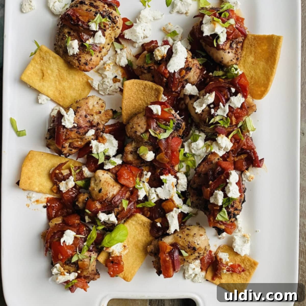 Platter of grilled chicken thighs with sautéed bruschetta and goat cheese
