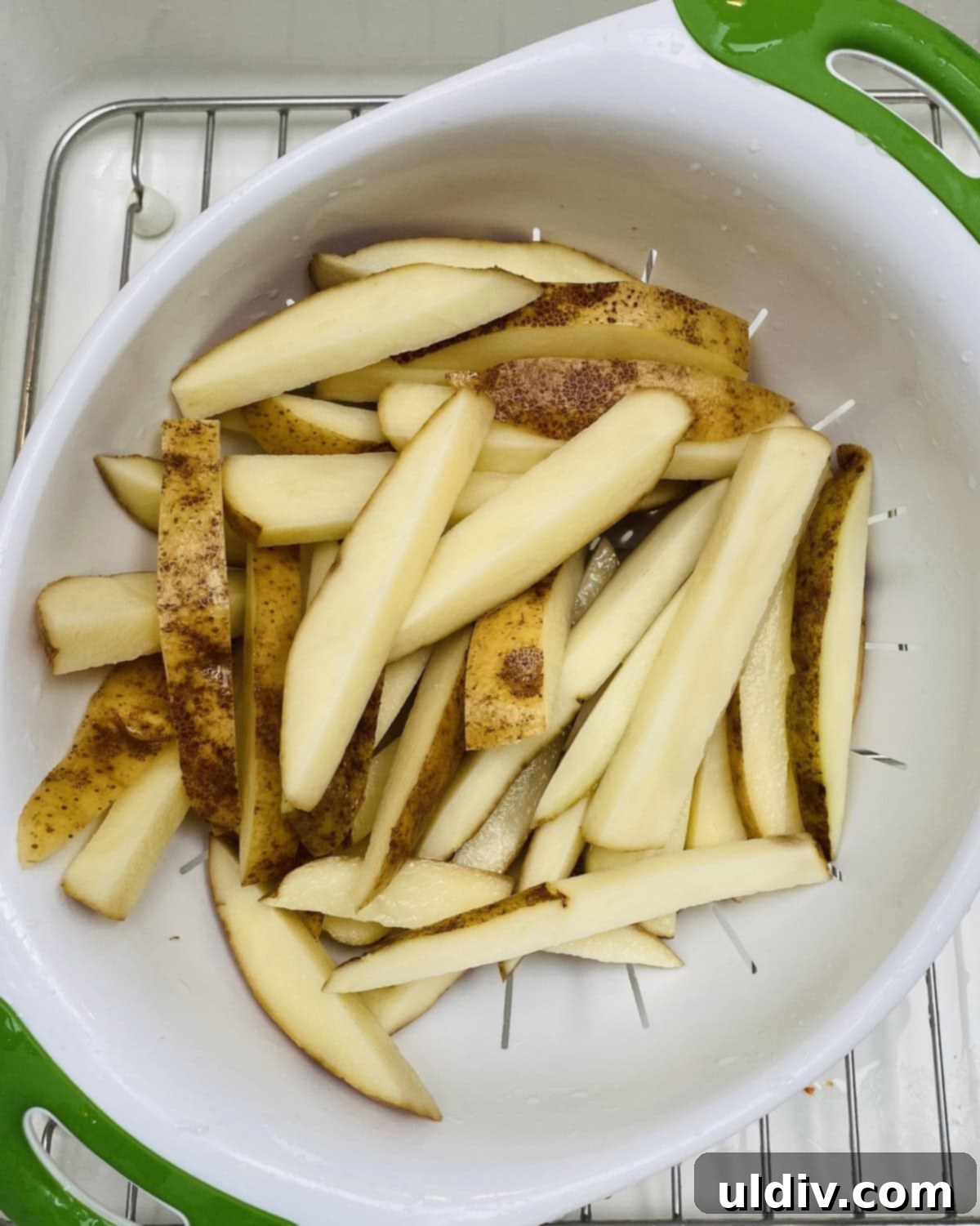 Homemade Crispy Oven Fries 6 Drained and blotted cut potatoes in a colander, ready for seasoning.