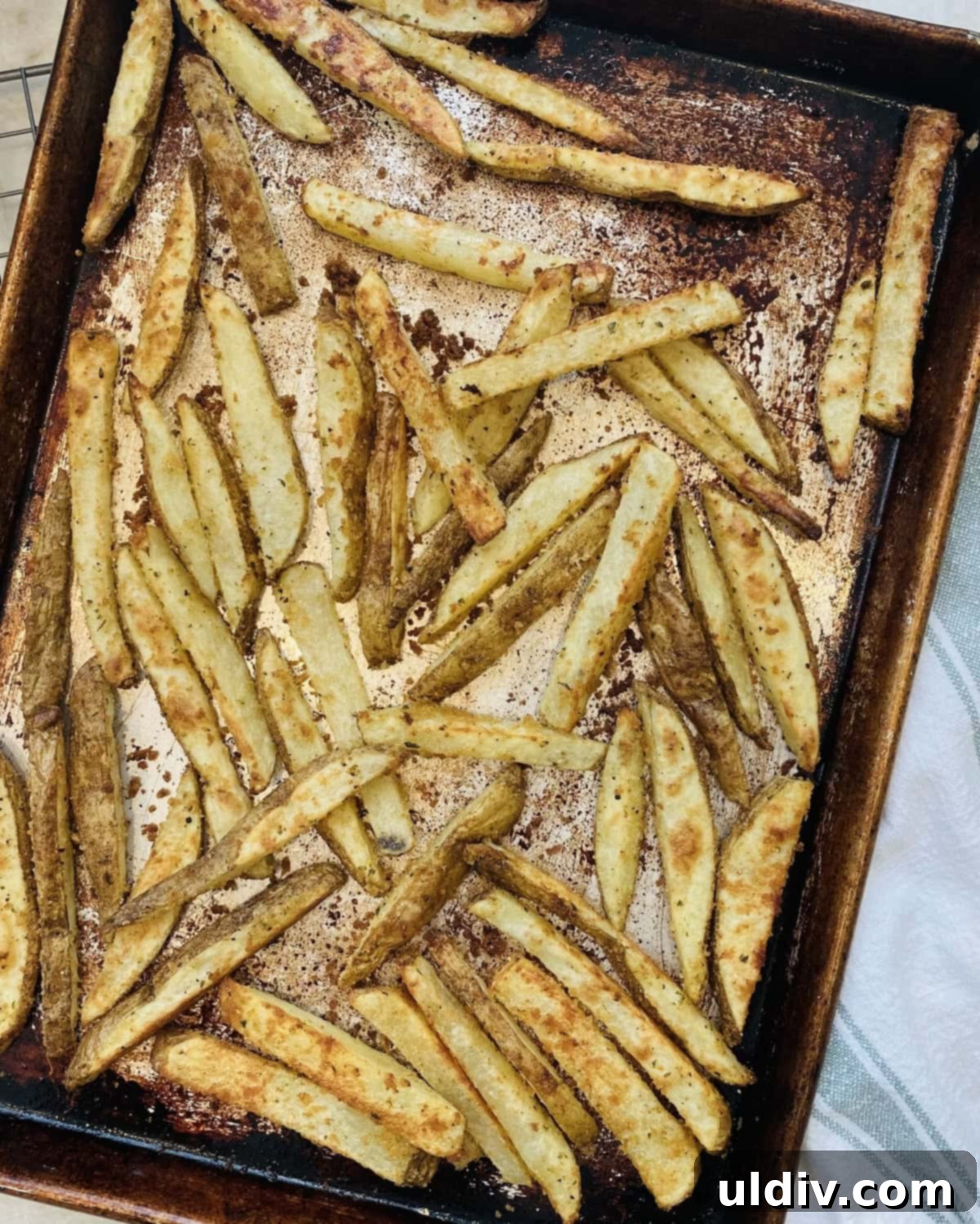 Homemade Crispy Oven Fries 9 A baking sheet filled with perfectly golden brown and crispy oven French fries, halfway through cooking.