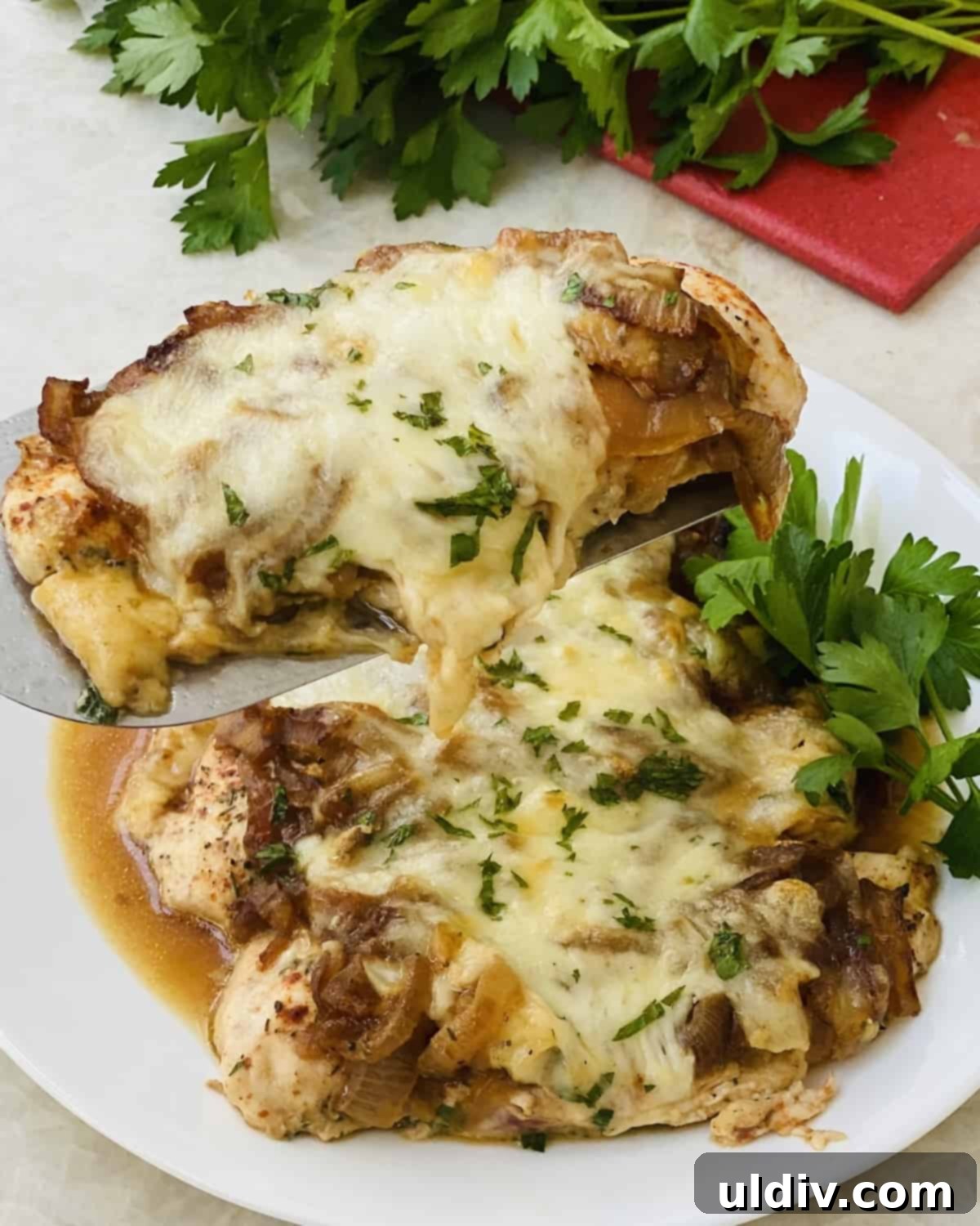 Classic French Onion Chicken Bake 2 A spatula with a piece of French Onion Chicken on it, showcasing melted cheese and caramelized onions.